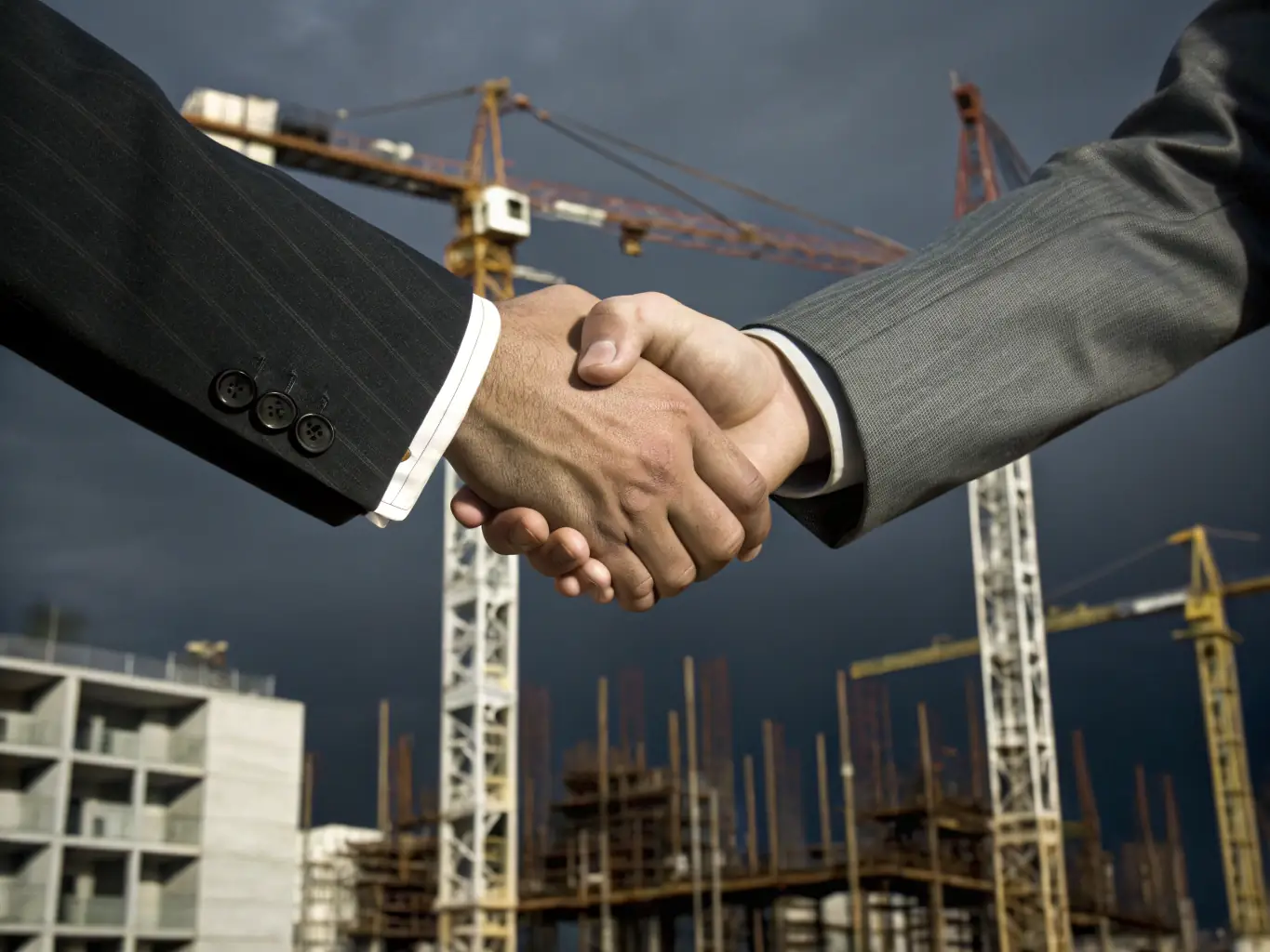 A satisfied client shaking hands with a Proobra.es project manager in front of a newly completed building, representing customer satisfaction.